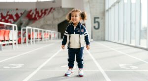 A high-quality, editorial-style photograph of a joyful toddler wearing a charming, stylish, and high