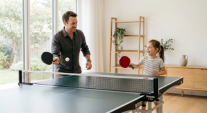 A professional, high-quality editorial shot of a parent and child happily practicing table tennis to