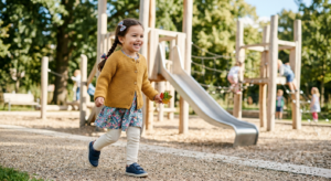 A professional, editorial-style photograph of a stylish and happy preschooler playing in a bright, m